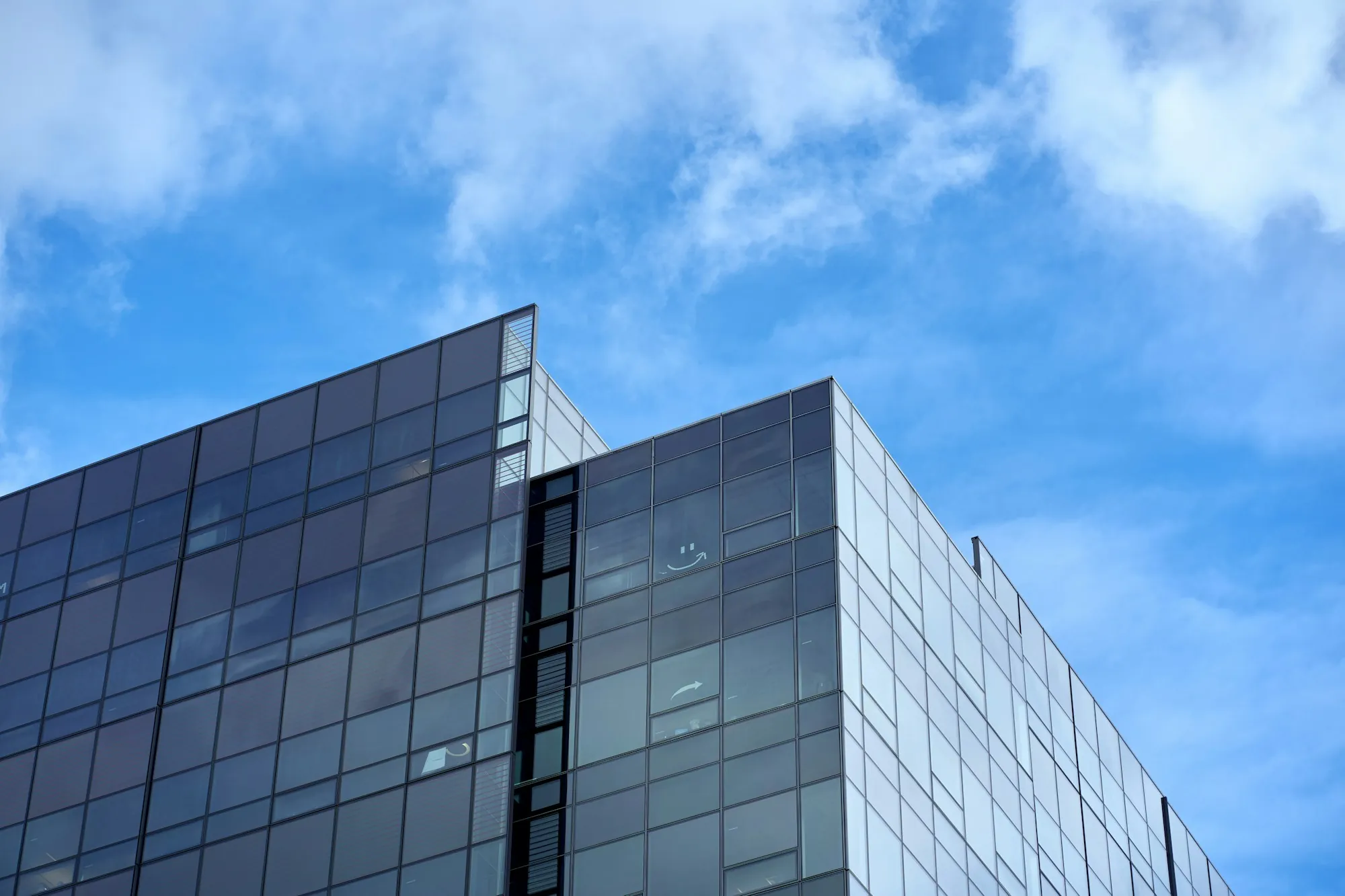 Glass office building under a blue sky with clouds