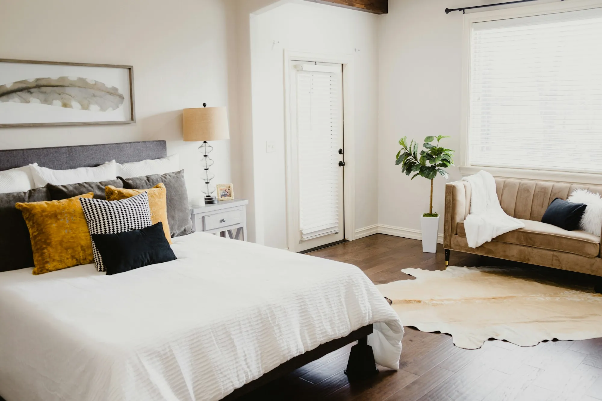 Bedroom with white bedding, throw pillows and a leather bench